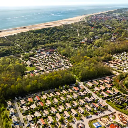 Luchtfoto van een vakantiepark achter de duinen, met het strand en de zee op de achtergrond