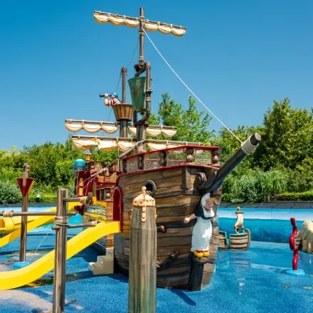 Piratenschip als speeltoestel in een waterspeeltuin, met een gele glijbaan ernaast